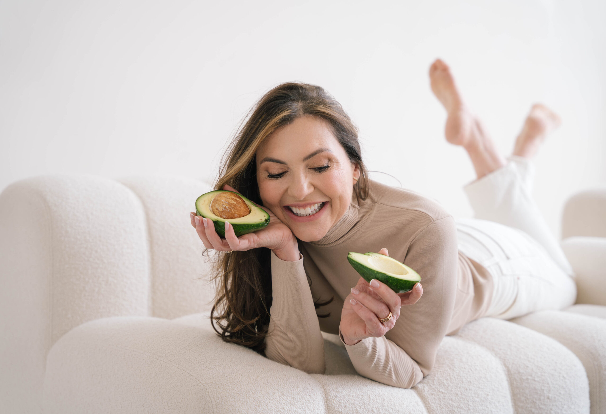 Marjena kijkend naar de zee, glimlachend in een roze v-hals trui