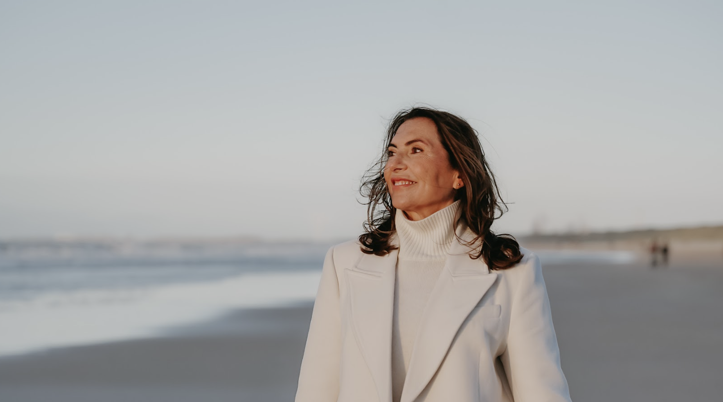 Marjena in een witte jas naar de zee kijkend