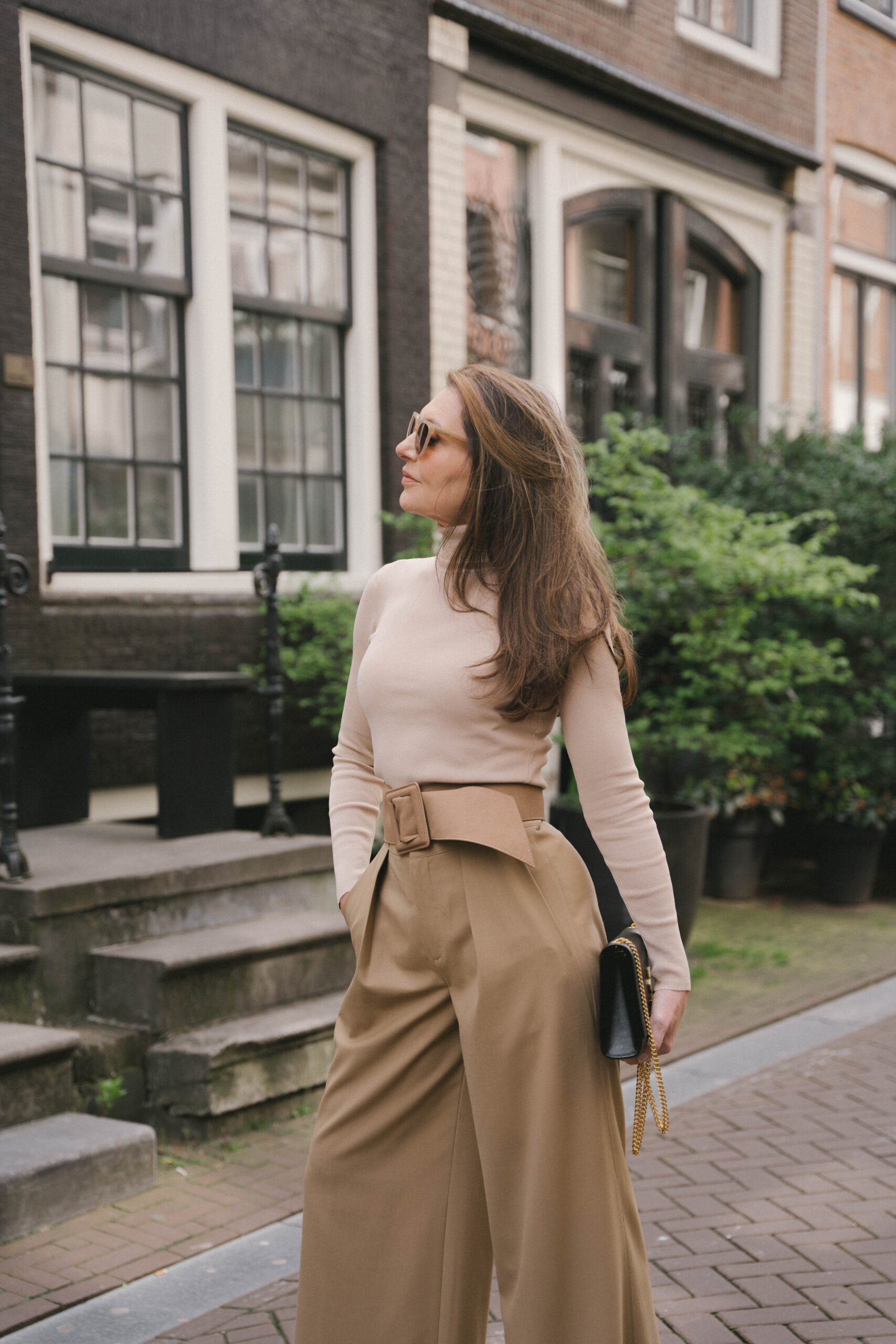 Jonge vrouw die lacht in de camera terwijl ze haar gebreide muts vasthoud